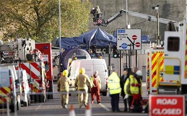 Workers survey the wreckage of the helicopter that hit the Clutha pub