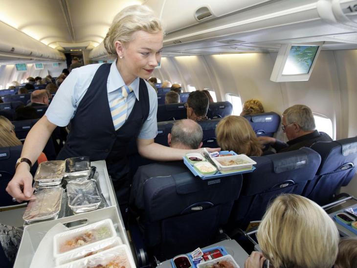 Flight attendant hands out food to passengers imageBROKER/REX