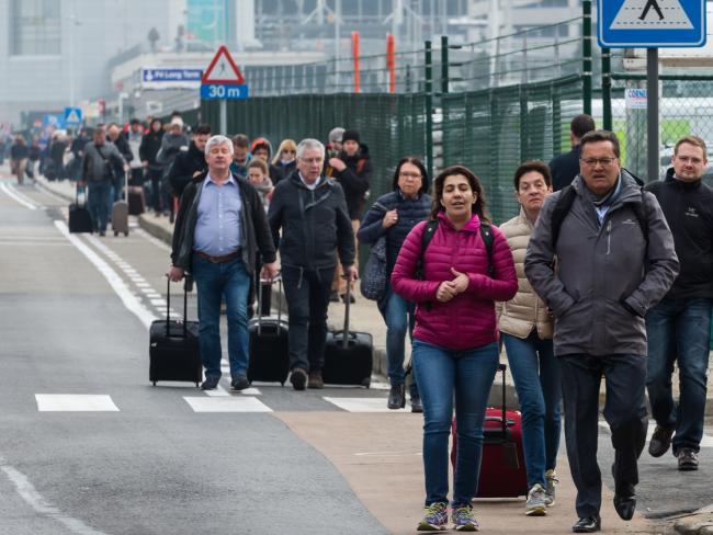 People walk away from Brussels airport after the explosions rocked the facility. Picture: AP / Geert Vanden Wijngaert